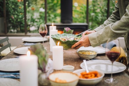 Person putting a green bowl on a table with food and candles