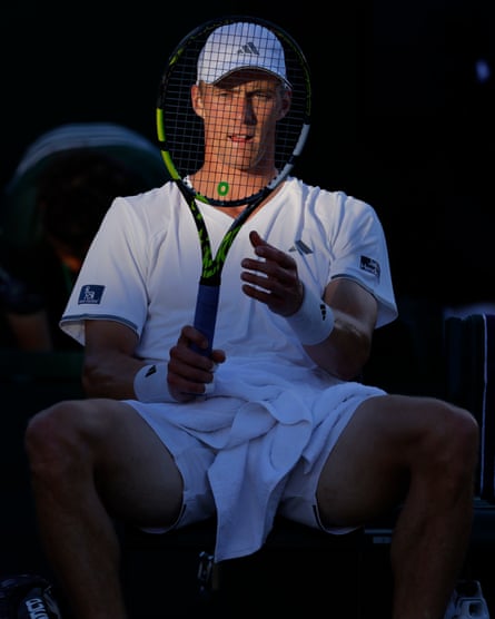 Jan Choinski looks dejectedly at his racket in a spot of reflected late evening sunshine