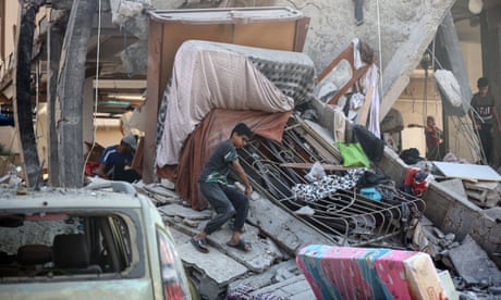 Palestinians boy inspecting the rubble after an Israeli bombardment, with beds and other furniture strewn