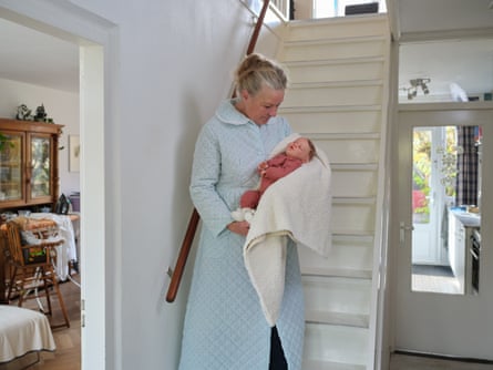 Ineke Schmelter stands in front of her white staircase and craddles her reborn doll, Norah, in her home in Bilthoven, in the Netherlands.