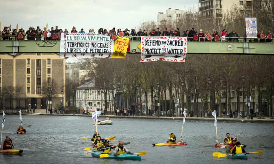 Indigenous people paddle down the Seine as others stand on a bridge holding banners during a rally in Paris demanding Indigenous rights are included in the climate accord on December 6, 2015 on the sidelines of the COP21 climate change conference. / AFP / LIONEL BONAVENTURELIONEL BONAVENTURE/AFP/Getty Images