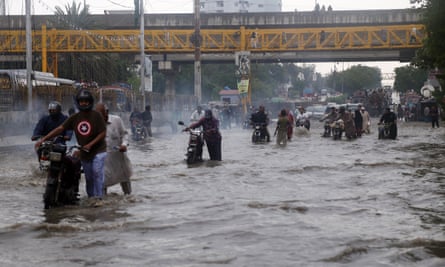 People make their way through flooded streets after a heavy downpour in Karachi on Thursday.