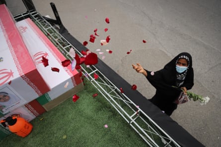 A woman throws rose petals on the coffins during a funeral of children killed in the air strike on a girls’ primary school in Minab, Iran.