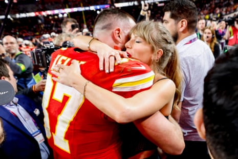 man in red football jersey hugs blonde woman, surrounded by crowd