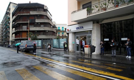 Shoppers queue up in the rain in Sicily.