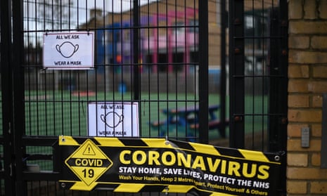 Signage reminding people to wear a mask and giving safety advice because of the coronavirus pandemic is seen on the closed gate of a primary school in east London on 3 January 2021
