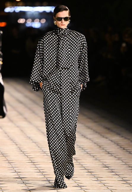 Model wears silky pyjamas in dark tones and polka dots.