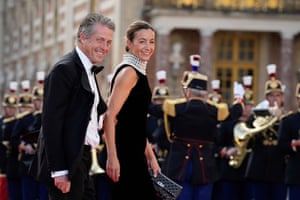 Hugh Grant and Anna Elisabet Eberstein smile as they walk along the red carpet