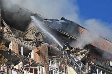 Firefighters work at a residential building damaged in a Russian drone strike in Kharkiv on 12 October amid the Russian invasion of Ukraine.