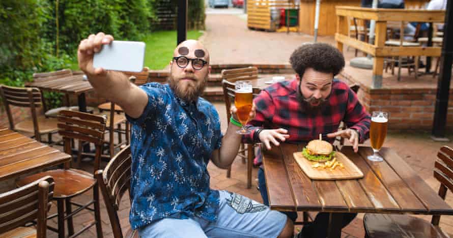 ‘A freebie is enough’: influencer gift posts trigger breaches in Australian ad standards A stock image showing two men posing for a selfie while showing off food and beer
