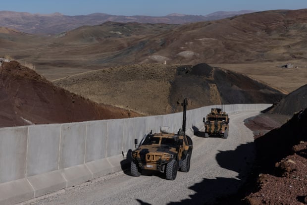 Turkish military vehicles patrol border wall