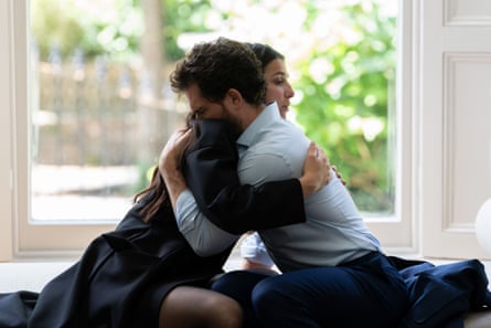 A woman and man embracing in front of a large window