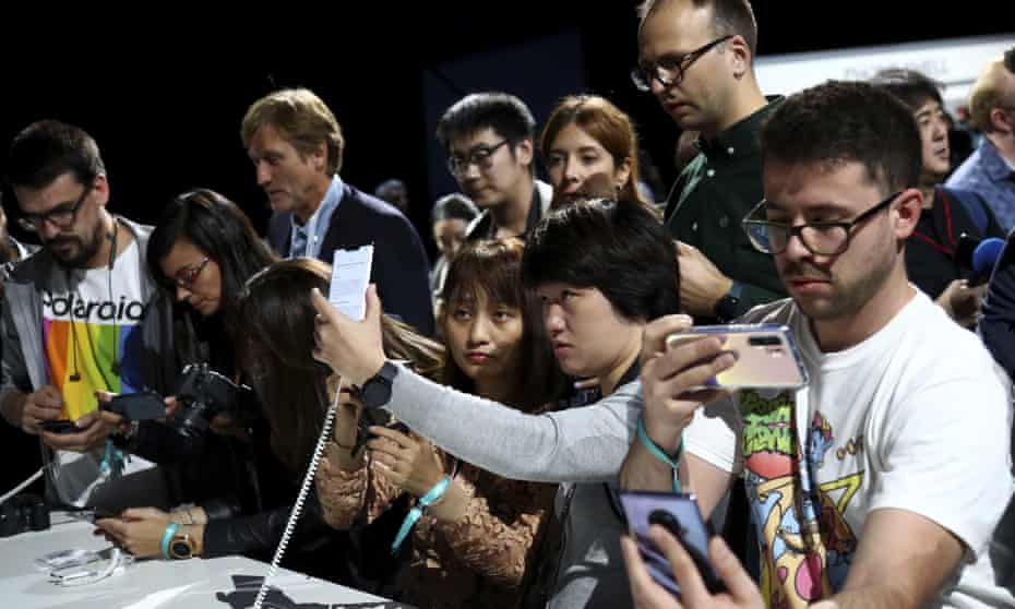Visitors take pictures of new devices of China’s smartphone manufacturer Huawei during an event in Germany