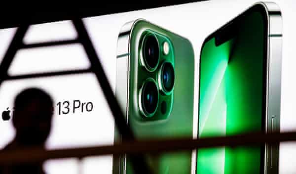 A person passes a large outdoor advertisement for the Apple iPhone 13 Pro in China