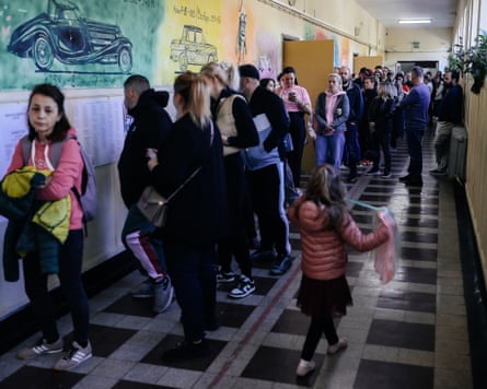 A queue of voters fills the length of a corridor in an institutional building