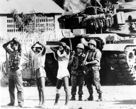 Two US soldiers guard three Grenadian prisoners in St George’s, Grenada in October 1983, with an American M-60 tank behind them