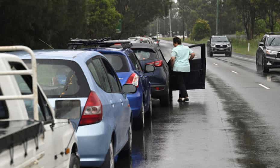 A woman in line at a Covid testing site in western Sydney steps out of her car to check the queue