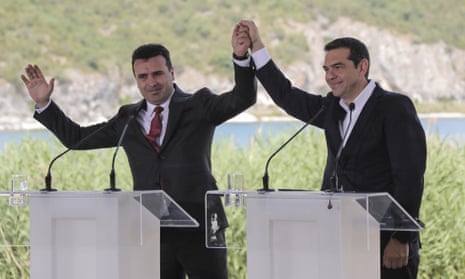 Zoran Zaev and Alexis Tsipras raise their hands during the signing ceremony at lake Prespa.