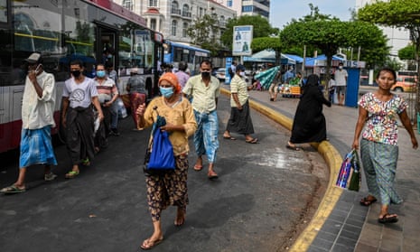 People walk along along a bus stop area in Yangon, Myanmar.