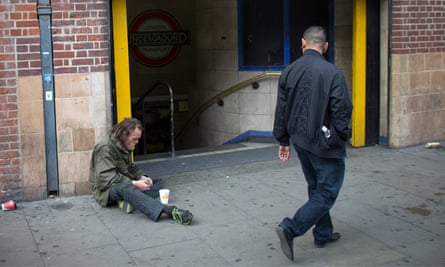 A man begs on a street in London, England.