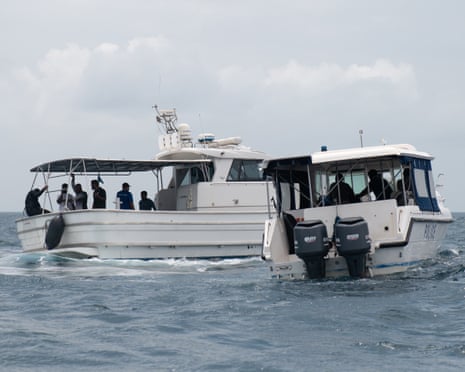 Two boats at sea with people onboard.