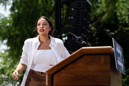 a woman in a white shirt speaks from behind a lectern
