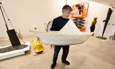Man holds large paper boat in gallery space