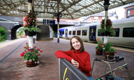 Mel Kennedy sitting at a train station with her walking frame beside her.