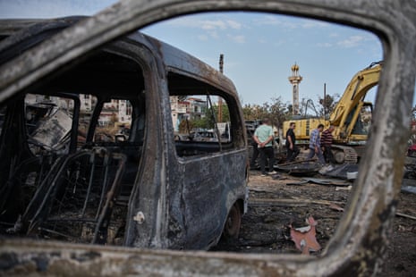 People walk past burnt cars and debris.