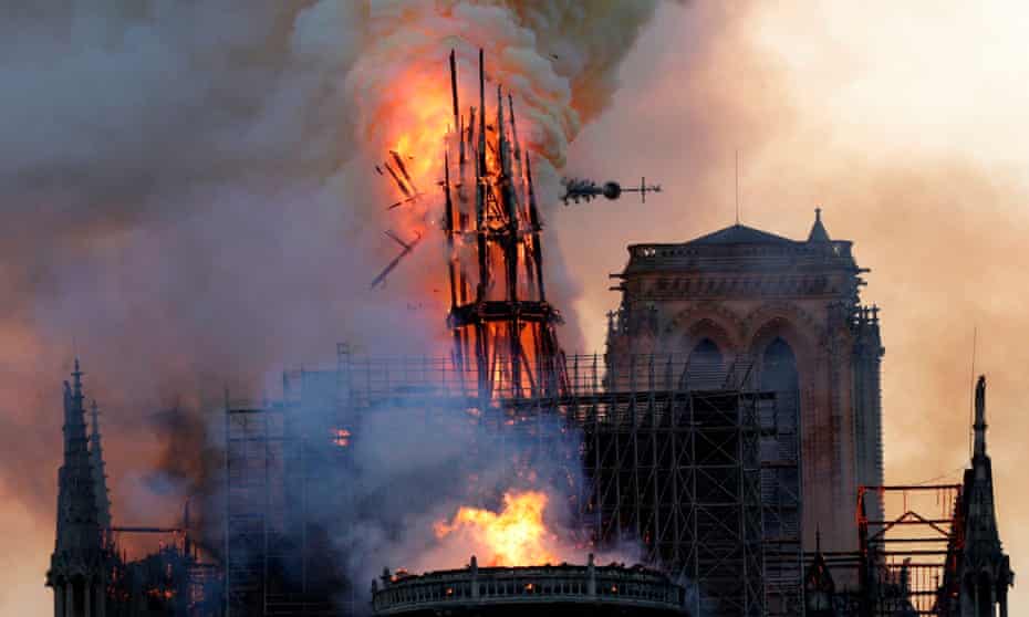 The spire of Notre Dame collapses, as smoke and flames engulf the cathedral.