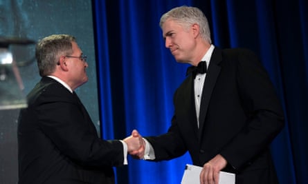 Two older men in suits shake hands.