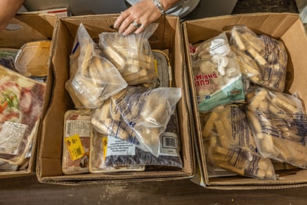 Detail of hands packing food items into three cardboard boxes