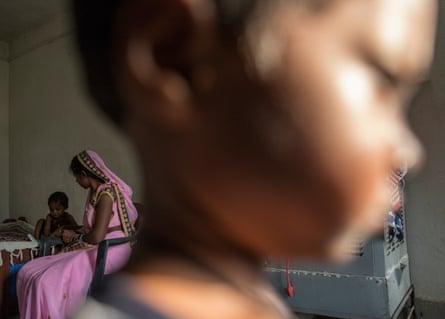A woman and her two children in their small house in the Basen resettlement built by Adani.