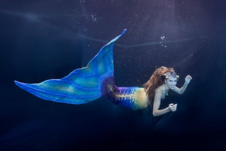 A woman with a large tail fin swimming underwater