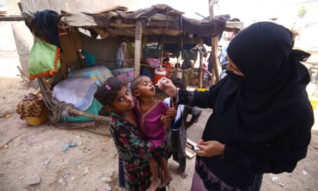 A health worker administers polio vaccine to children