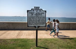 Young girls walk past a sign denoting the 400th anniversary of the landing of the first enslaved Africans in English-occupied North America at Point Comfort in 1619.