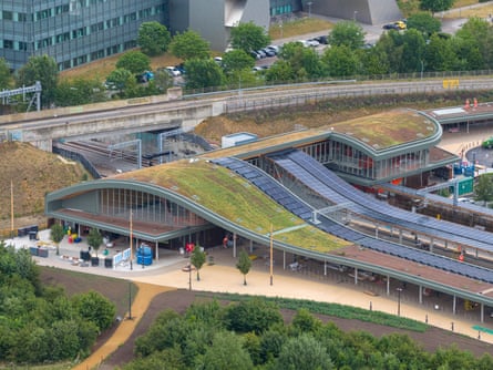 A train station with curved roof planted with grass and flowers