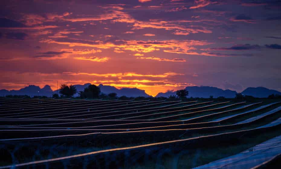 A beautiful red-gold sunset over a field full of rows and rows of solar panels