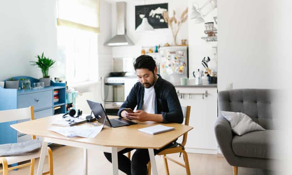 Asian man using smart phone while working from home<br>Photo series of japanese man working from home as a freelancer, making conference calls and discussing projects.