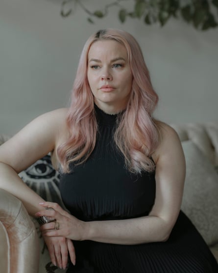 A woman with pink hair poses on a couch