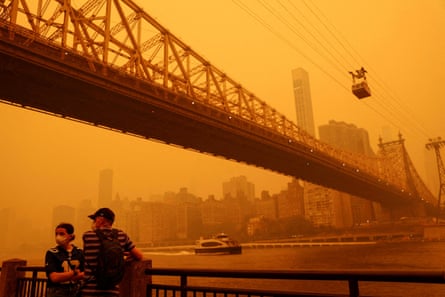 people standing by a bridge with a hazy orange sky ahead