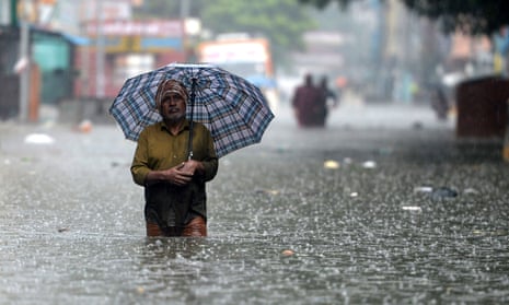 A man wades through a flooded street after heavy monsoon rains in Chennai, India, 8 November.