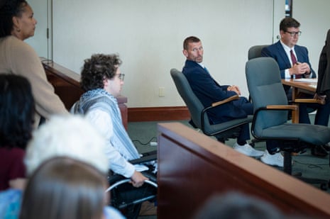 Jason Eaton watches as Hisham Awartani arrives in a wheelchair to testify in court