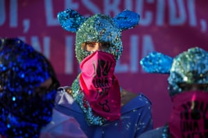 Demonstrators wear scarves over their faces with the words ‘Not one less’ 