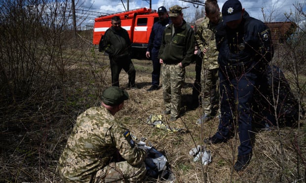 Officials look at shards of twisted metal from a Russian rocket in undergrowth near a train line near Lviv