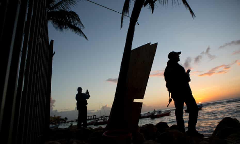 Municipal police watch the sunrise as they stand guard on the beach in front of the Blue Parrot club, a day after a deadly early morning shooting, in Playa del Carmen, just south of Cancún.