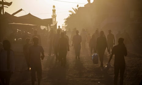 Displaced Palestinians walk through a street market in Khan Younis, southern Gaza, on Saturday