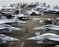 A US Navy officer walks past fighter jets parked on the flight deck of the Nimitz-class aircraft carrier USS Abraham Lincoln.