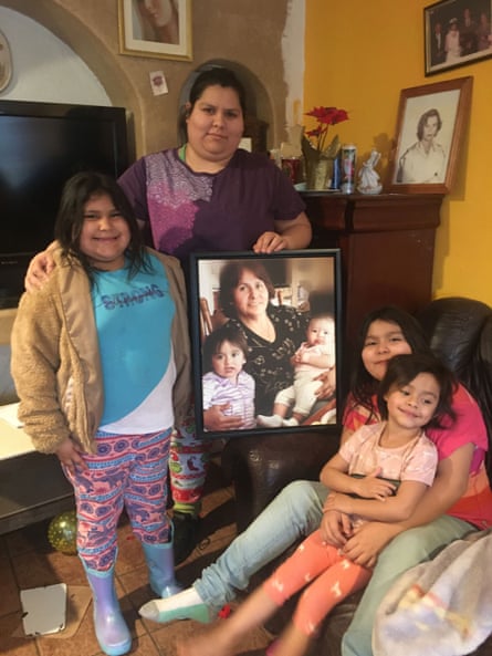 Maria Orozco in her home with her young daughters and niece, holding a photo of her mother, who died advocating for clean water.