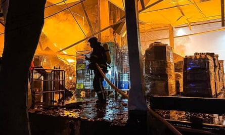 A firefighter spraying water in a warehouse in Odesa after an overnight strike
